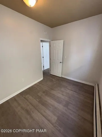 a view of an empty room with wooden floor and closet