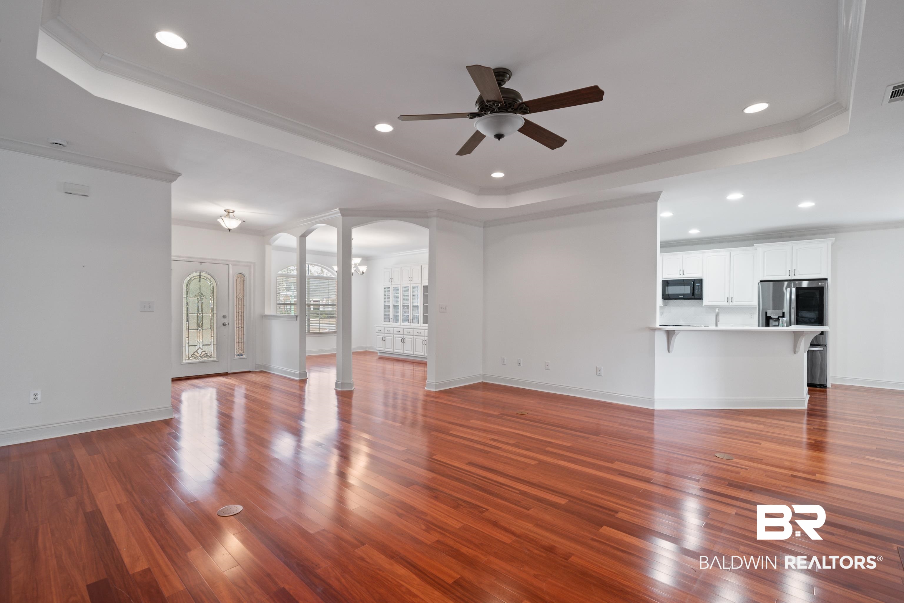 404 Savannah Lane Foley, AL 36535 - Photo 9 of 29 Unfurnished living room featuring arched walkways, a raised ceiling, ornate columns, and wood finished floors