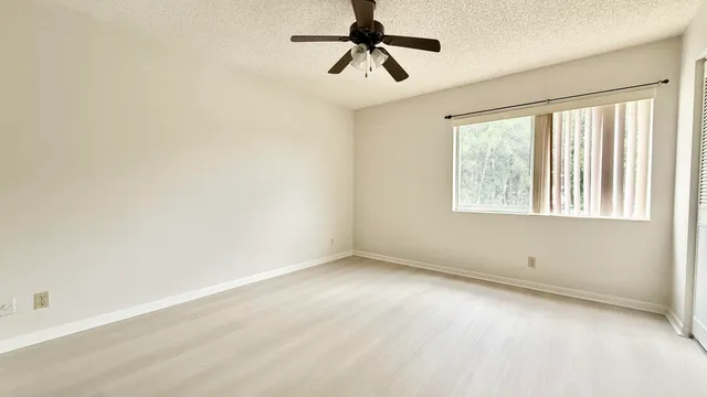 an empty room with windows and fan