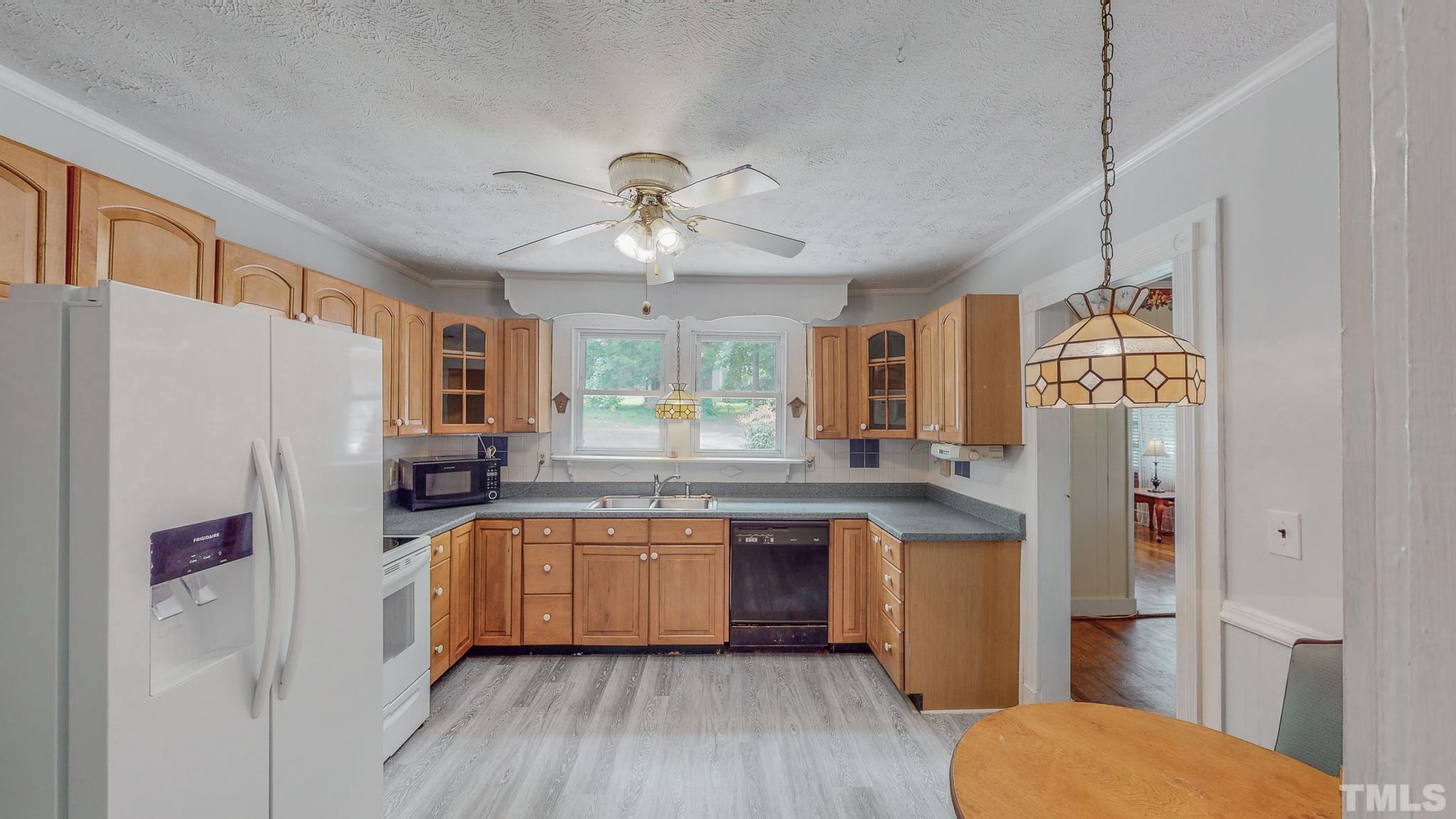 1556 Gentry-Dunkley Road Roxboro, NC 27574 - Photo 3 of 47 a kitchen with stainless steel appliances a refrigerator a sink dishwasher a stove and white countertops with wooden floor