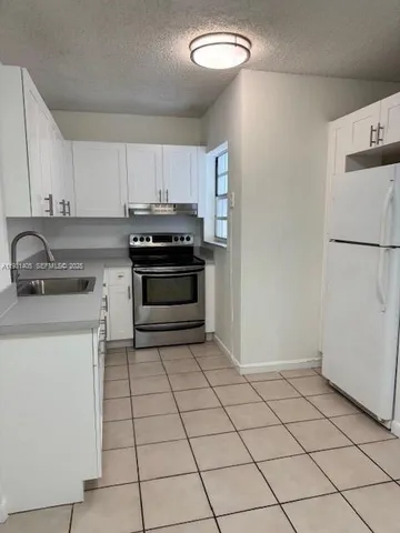 a kitchen with a sink a stove and white cabinets
