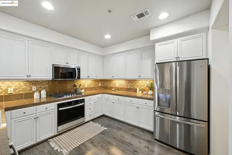 a kitchen with white cabinets and stainless steel appliances