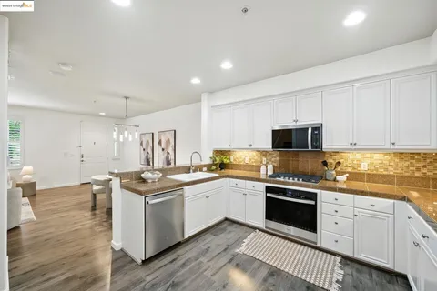 a kitchen with stainless steel appliances a sink stove and wooden floor