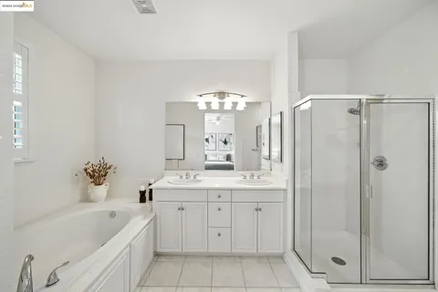 a bathroom with a double vanity sink large mirror and a bathtub