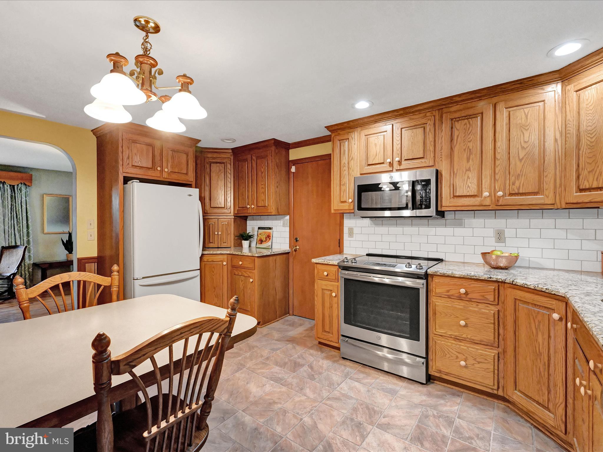 827 Pine Hill Road Lititz, PA 17543 - Photo 8 of 34 a kitchen with stainless steel appliances granite countertop a stove a refrigerator a kitchen island a sink dishwasher a dining table and chairs with wooden floor