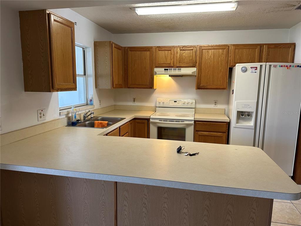 2454 Pine Chase Circle St. Cloud, FL 34769 - Photo 2 of 10 a kitchen with a sink a stove and a refrigerator