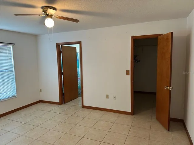 an empty room with closet and a chandelier fan