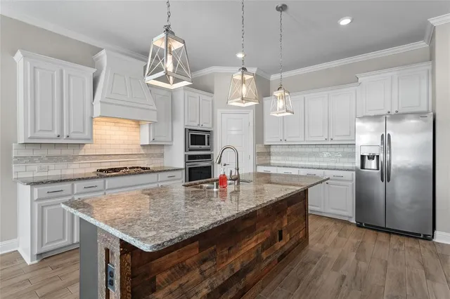 a kitchen with stainless steel appliances granite countertop a kitchen island a stove and a sink