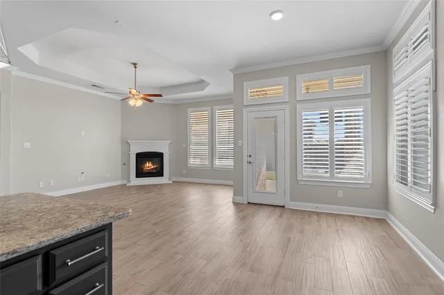 an empty room with wooden floor fireplace and windows