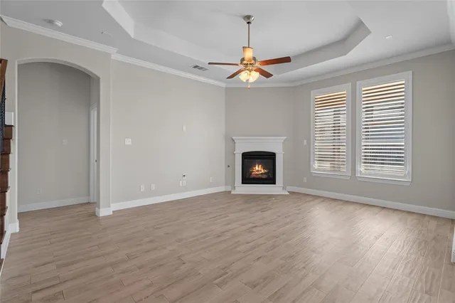 a view of an empty room with wooden floor fireplace and a window