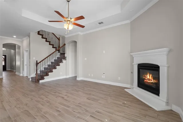 a view of an empty room with wooden floor a fireplace and a chandelier