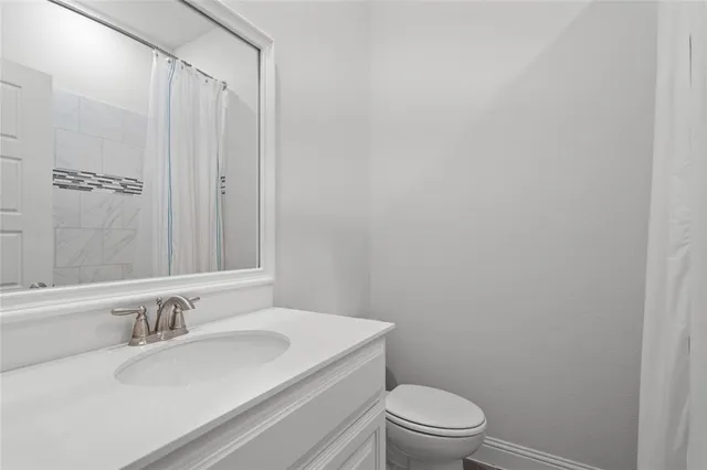 a bathroom with a granite countertop sink a toilet and a mirror