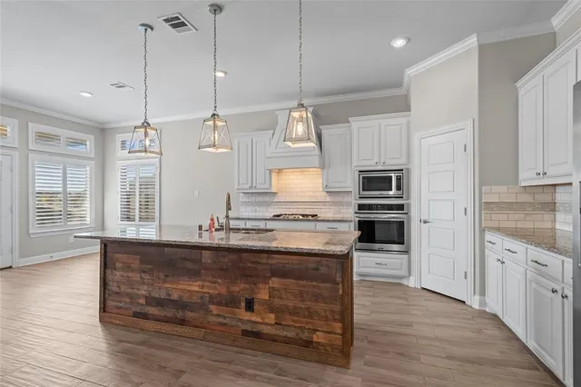a kitchen with stainless steel appliances granite countertop a sink a stove and a wooden floor