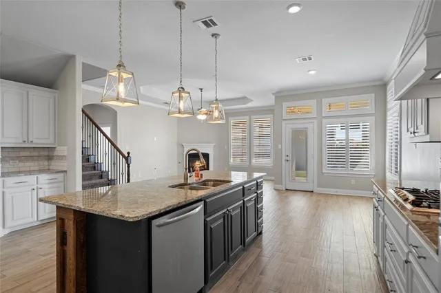 a kitchen with stainless steel appliances granite countertop a stove a sink dishwasher a refrigerator and a dining table with wooden floor