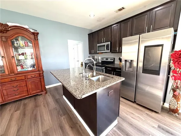 a kitchen with kitchen island granite countertop a refrigerator a stove top oven a sink and dishwasher with wooden floor