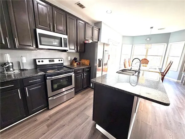 a kitchen with kitchen island granite countertop a sink appliances and cabinets