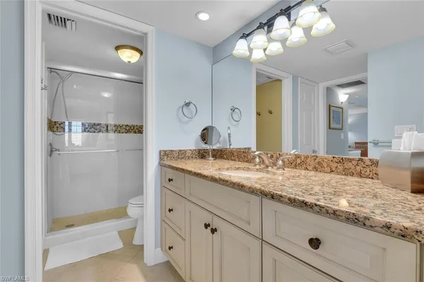 a bathroom with a granite countertop sink a large mirror and a shower