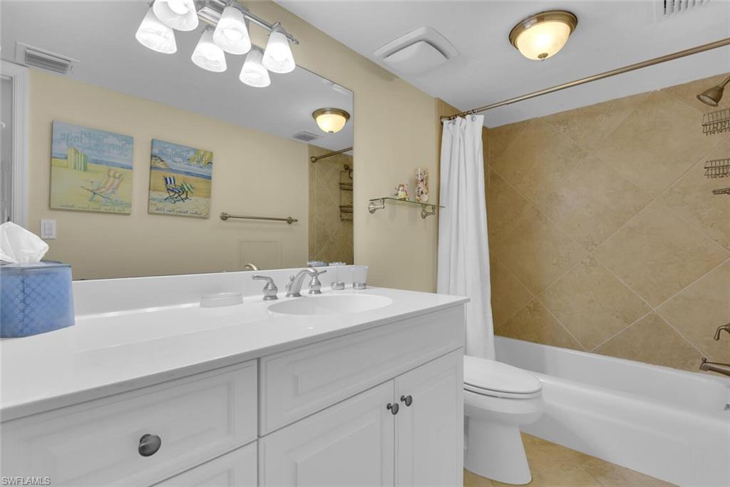 3443 Gulf Shore Boulevard North, Unit 710 Naples, FL 34103 - Photo 20 of 29 a bathroom with a sink a toilet and a large mirror
