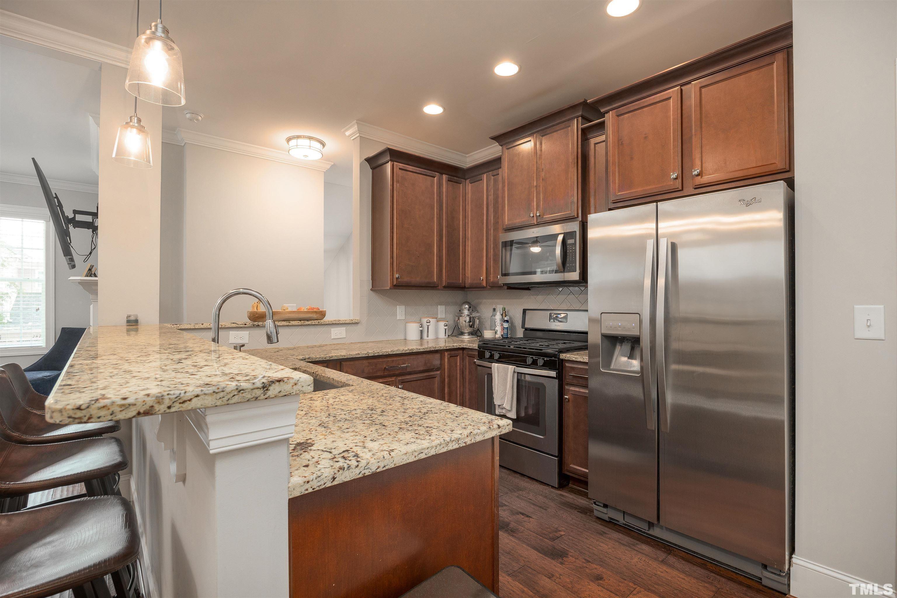 2829 Plumfield Place Raleigh, NC 27607 - Photo 5 of 26 a kitchen with kitchen island granite countertop a sink stove and refrigerator