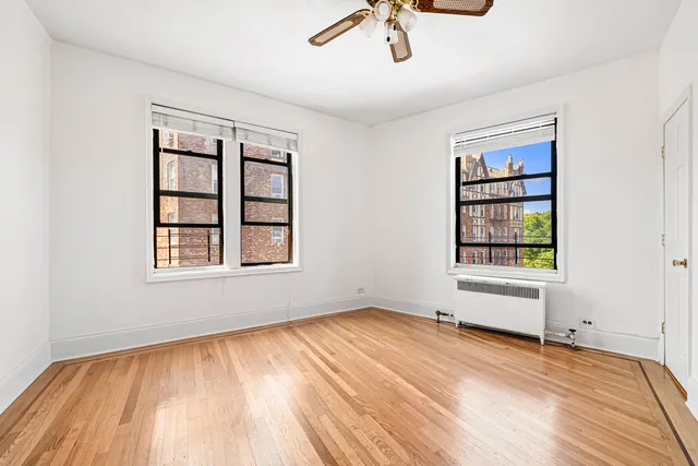 a view of an empty room with a window and wooden floor