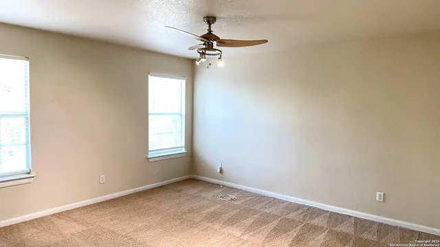 an empty room with a window and a fan