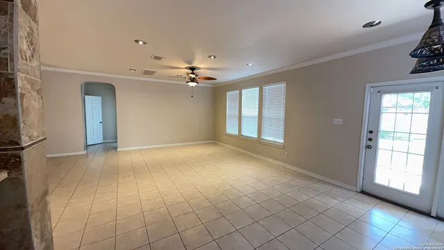 a view of an empty room with window and chandelier fan