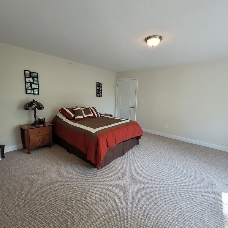 130 Spring Street, Unit 202 Mansfield, MA 02048 - Photo 12 of 23 a spacious bedroom with a bed and a lamp