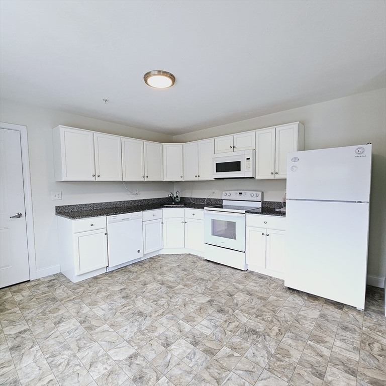 130 Spring Street, Unit 202 Mansfield, MA 02048 - Photo 2 of 23 a kitchen with granite countertop white cabinets and white appliances