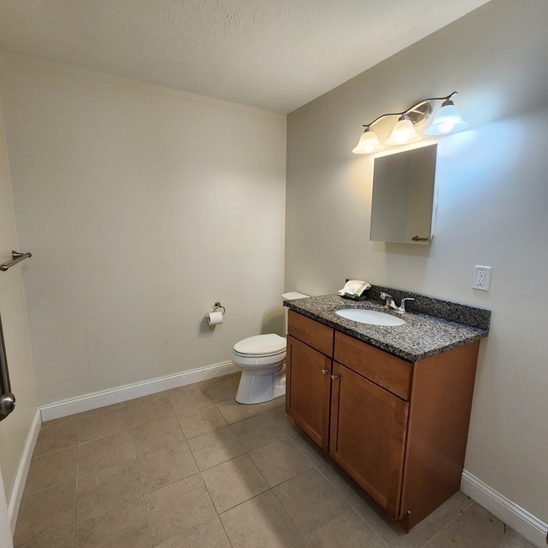 130 Spring Street, Unit 202 Mansfield, MA 02048 - Photo 9 of 23 a bathroom with a sink and mirror with toilet