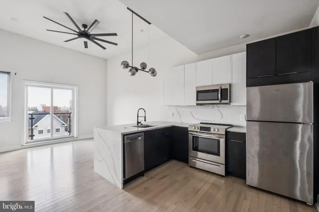 a kitchen with stainless steel appliances a stove a refrigerator sink cabinets and wooden floor