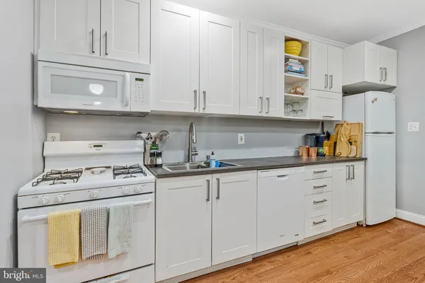 a kitchen with granite countertop white cabinets and white appliances