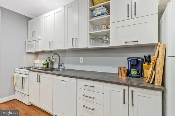 a kitchen with granite countertop white cabinets and white appliances