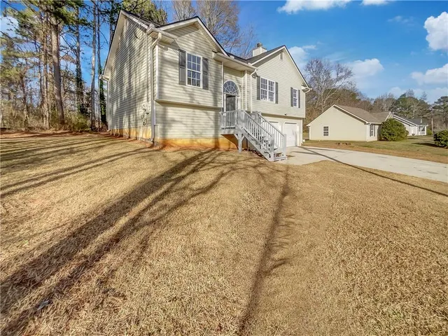 a view of a white house with a large trees next to a road