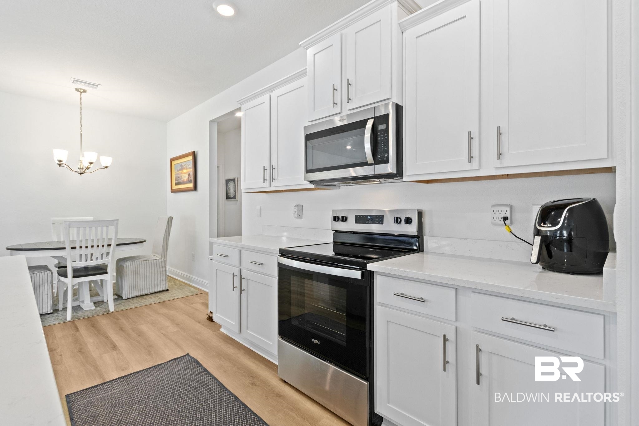 12919 Torrent Road Fairhope, AL 36532 - Photo 24 of 74 Kitchen featuring stainless steel appliances, white cabinetry, light wood-style floors, light stone counters, and a chandelier