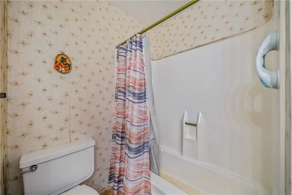 a bathroom with a toilet and a shower curtain