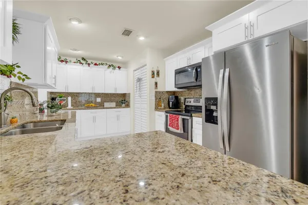 a kitchen with stainless steel appliances kitchen island granite countertop a refrigerator and a sink