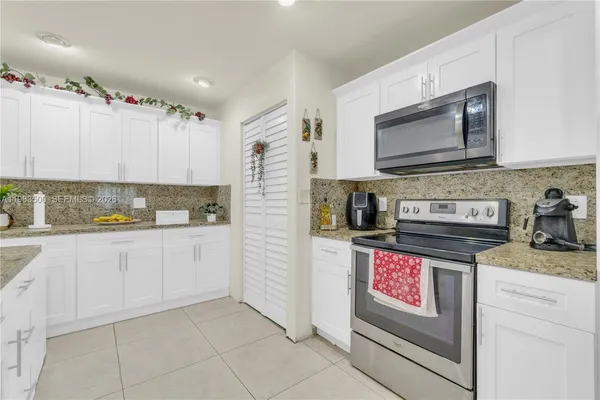 a kitchen with granite countertop a stove top oven microwave and cabinets