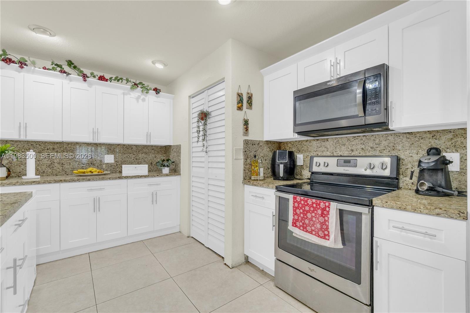 12691 Southwest 190th Street Miami, FL 33177 - Photo 6 of 46 a kitchen with granite countertop a stove top oven microwave and cabinets