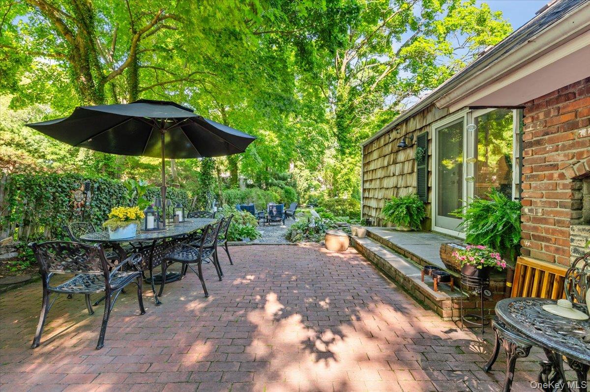 10 Rancher Place Huntington, NY 11743 - Photo 32 of 44 Brick paver patio with a cedar shake siding exterior, full-lite glass door, and an outdoor brick fireplace
