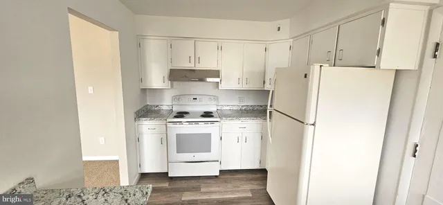 a kitchen with stainless steel appliances a refrigerator a stove and white cabinets