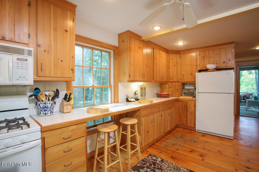 142 Main Road Monterey, MA 01230 - Photo 16 of 32 a kitchen with granite countertop a refrigerator a sink dishwasher stove and white cabinets with wooden floor