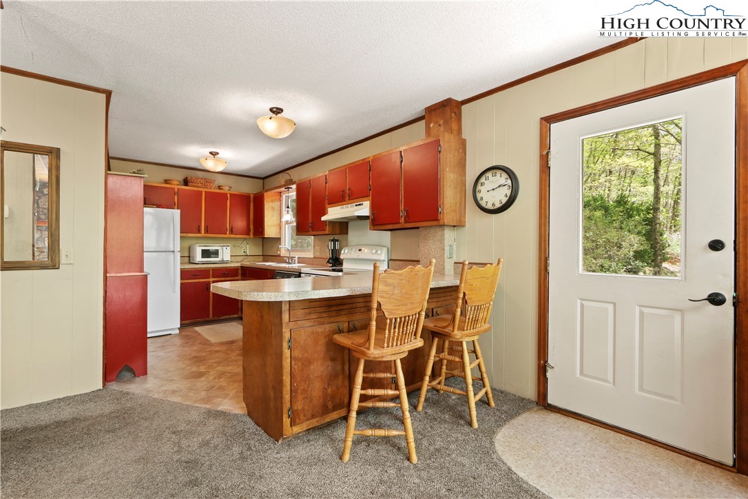 845 Trout Lake Road Deep Gap, NC 28618 - Photo 8 of 38 a kitchen with stainless steel appliances granite countertop a stove a refrigerator a microwave oven with white cabinets and wooden floor