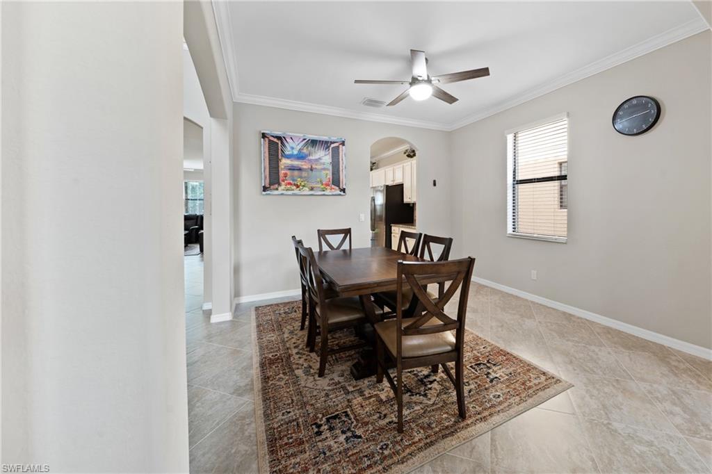 4228 Raffia Palm Circle Naples, FL 34119 - Photo 12 of 50 Dining space with arched walkways, crown molding, a ceiling fan, and light tile patterned floors