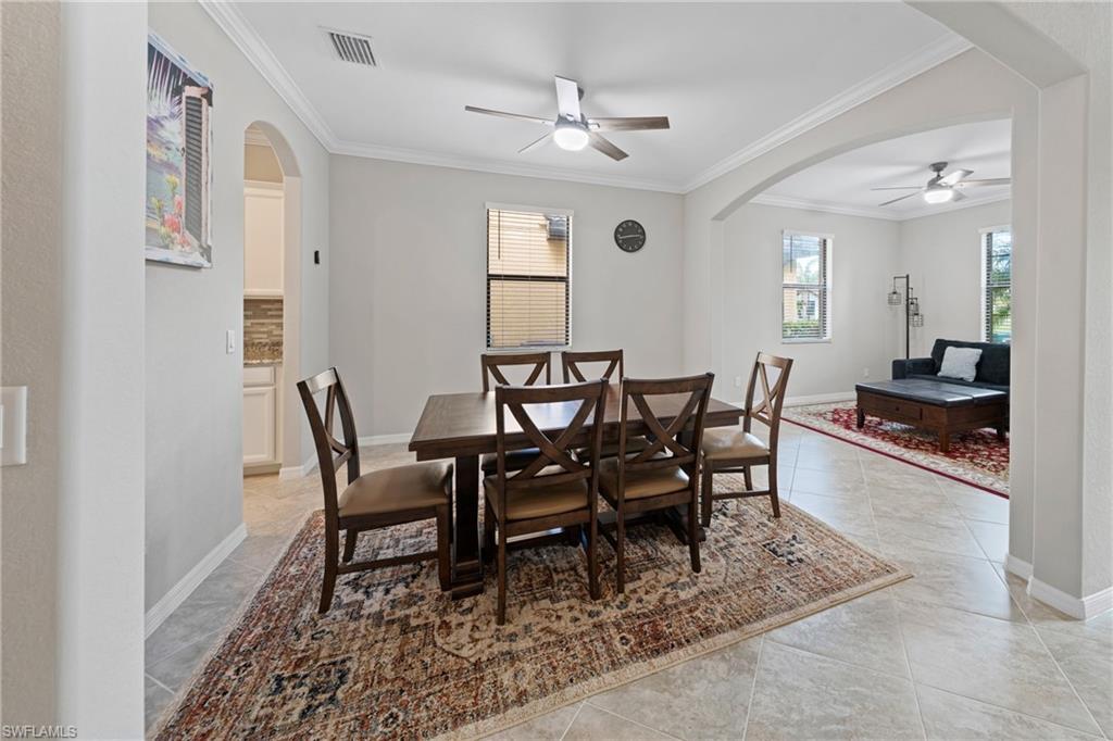 4228 Raffia Palm Circle Naples, FL 34119 - Photo 13 of 50 Dining area with arched walkways, ceiling fan, crown molding, healthy amount of natural light, and light tile patterned floors
