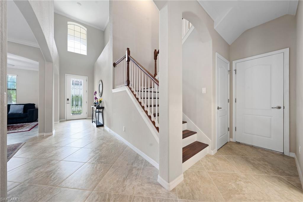 4228 Raffia Palm Circle Naples, FL 34119 - Photo 14 of 50 Entrance foyer featuring arched walkways, a high ceiling, light tile patterned flooring, ornamental molding, and stairway