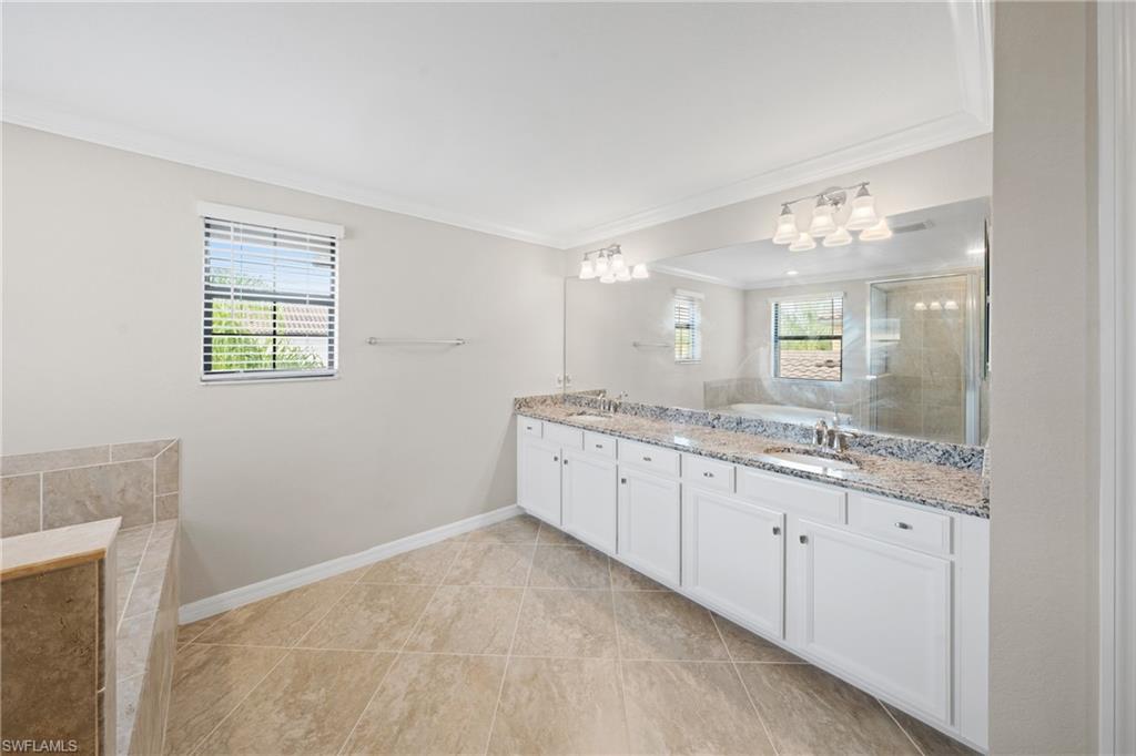 4228 Raffia Palm Circle Naples, FL 34119 - Photo 18 of 50 Full bathroom with ornamental molding, double vanity, a bath, and light tile patterned floors