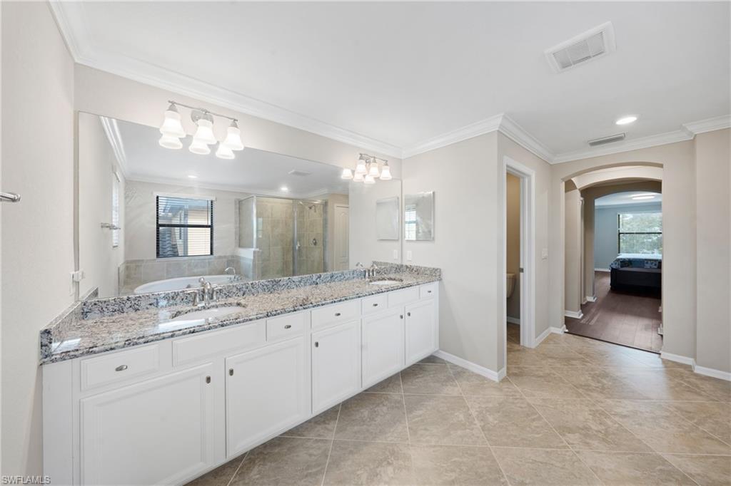 4228 Raffia Palm Circle Naples, FL 34119 - Photo 20 of 50 Ensuite bathroom featuring a shower stall, crown molding, a bath, double vanity, and light tile patterned floors