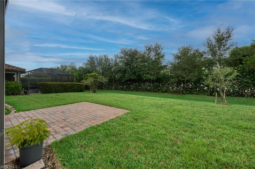 4228 Raffia Palm Circle Naples, FL 34119 - Photo 34 of 50 View of grassy yard with a patio, a sunroom, and glass enclosure