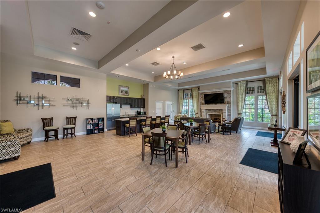 4228 Raffia Palm Circle Naples, FL 34119 - Photo 43 of 50 Dining space with a raised ceiling, a fireplace, a chandelier, and recessed lighting