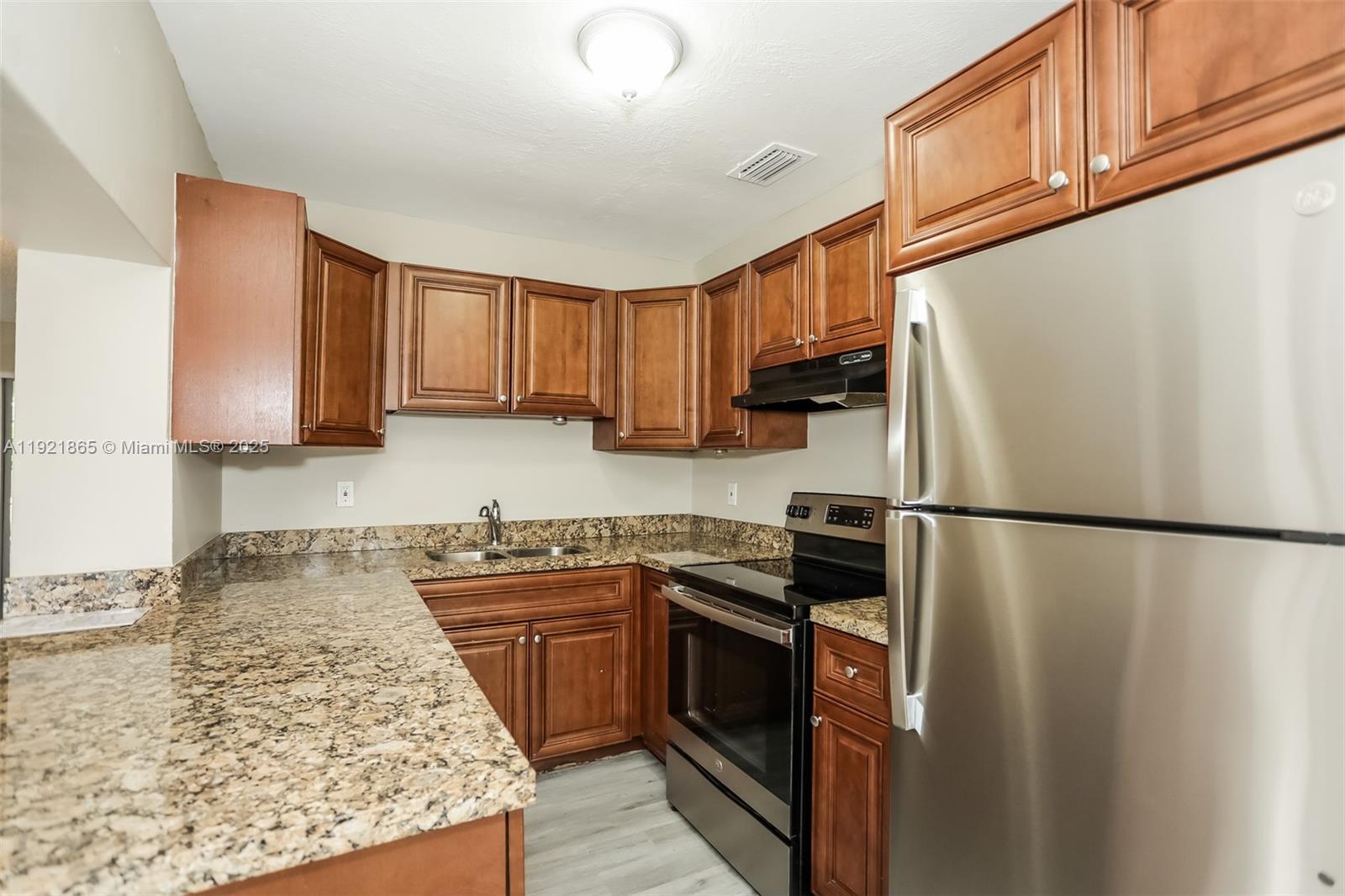 5835 Southwest 117th Avenue Miami, FL 33173 - Photo 6 of 16 a kitchen with a sink a refrigerator and a stove top oven